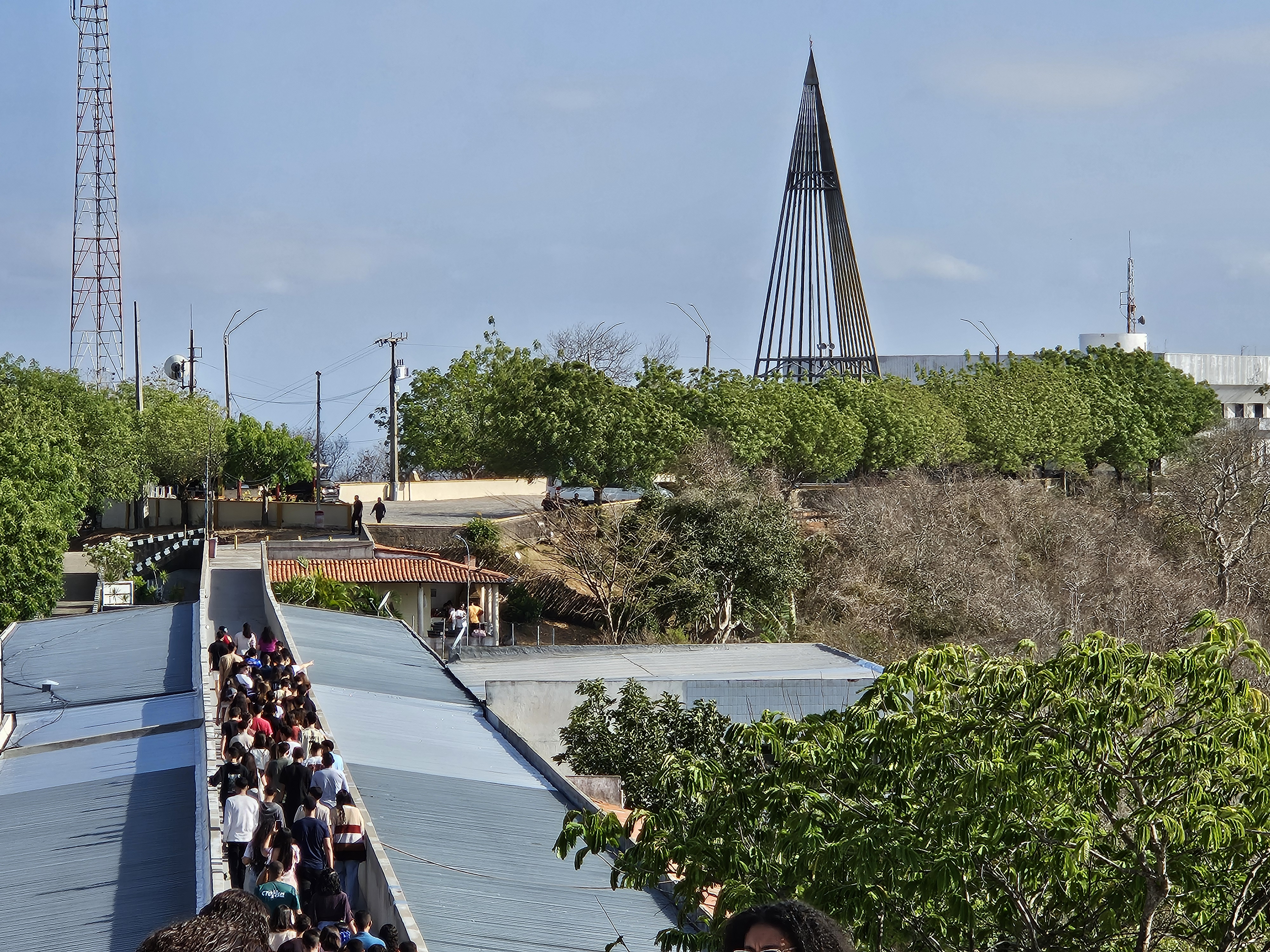 Fachada de igreja com cruz vermelha no topo e céu azul ao fundo